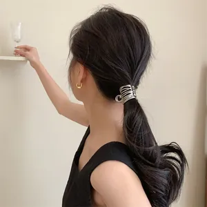 Détail de style de vie d'une pince à cheveux argentée plissée sur cheveux foncés