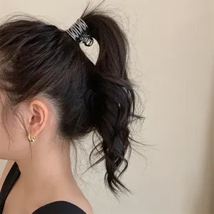 Pince à cheveux géométrique argentée au design plissé irrégulier sur une queue de cheval