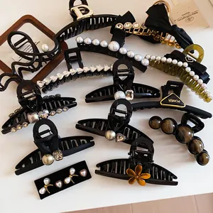 Close-up of elegant black French hair claws decorated with pearls and rhinestones