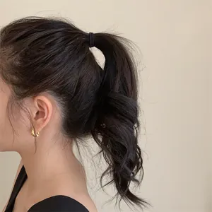 Vue détaillée d'une pince à cheveux géométrique dorée sur une queue de cheval