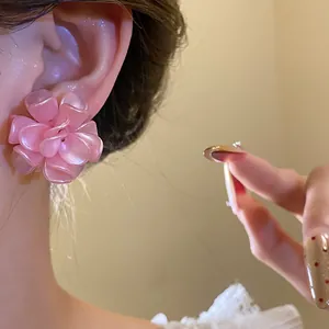 Detailed close-up showing a pink pearlescent multi-layer flower stud earring worn on ear