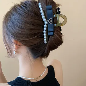 Elegant French style black ribbon hair claw clip with pearls and heart detail on model
