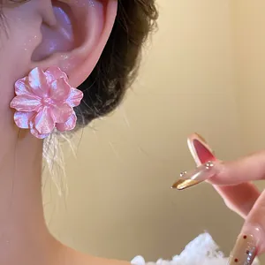 Detailed close-up view of a sweet pink pearlescent flower stud earring worn on an ear