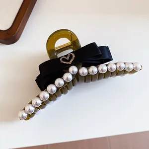 Close-up detail of French pearl hair claw clip with black ribbon bow and crystal heart