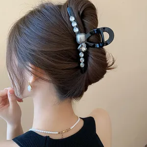 Close-up of an elegant black hair claw clip with rhinestones in a French bun hairstyle.