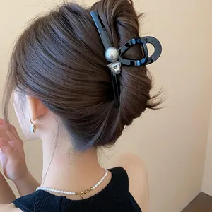 Elegant black pearl hair claw clip with heart crystal on model's bun hairstyle.