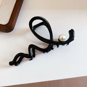 Detail shot of an elegant French style black hair claw clip with a decorative pearl