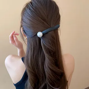 Close-up of an elegant French style black hair clip with a large pearl worn on brown hair.