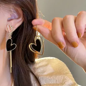 Boucles d'oreilles cœur asymétriques dorées avec incrustation noire et pompons