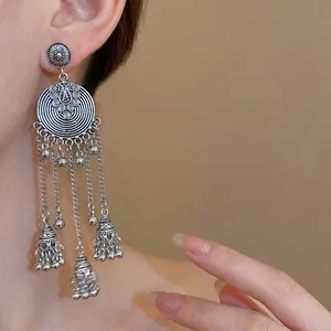 Vintage Bohemian silver tassel earrings with round disc and bell charms on model
