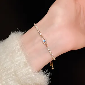 Elegant gold tennis bracelet with zircon evil eye charm on a female model's wrist