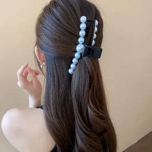 Detailed shot of an elegant black hair claw clip adorned with large white pearls.