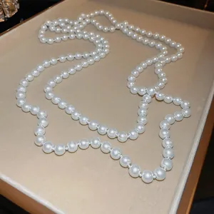 Elegante lange Perlenkette für Pullover auf einem beigen Samt-Schmucktablett