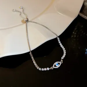 Detail view of sparkling zircon Evil Eye charm on silver-toned adjustable bracelet