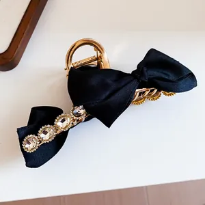 Detailed macro shot of the black ribbon bow and rhinestone embellishments on hair clip.