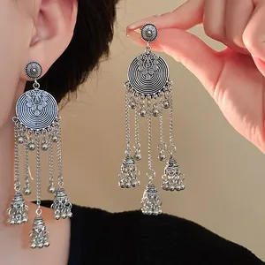 Bohemian vintage silver needle tassel earrings with round bell drops, close-up detail.