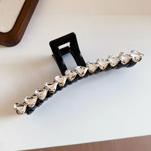 Detailed macro view of elegant black hair claw clip with sparkling heart-shaped crystals