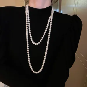 Elegante lange doppellagige weiße Perlenkette getragen auf einem schwarzen Oberteil