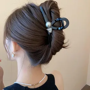 Close-up of elegant black hair claw clip with pearl on woman's bun hairstyle