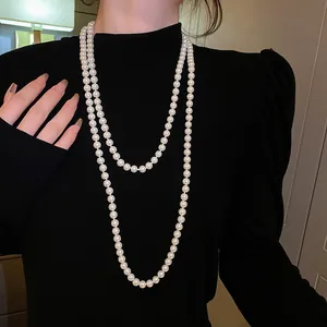 Elegante lange doppellagige weiße Perlenkette über einem schwarzen Pullover getragen