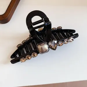 Detail of black hair claw clip with brownish-grey rhinestone heart and square accents