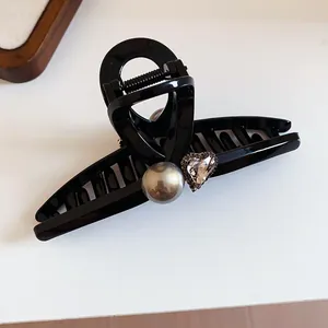 Close-up of black French style hair claw clip with pearl and heart crystal detail