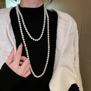 Detailansicht einer eleganten langen Perlenkette getragen über einem schwarzen Pullover