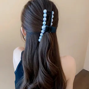 Elegant black hair claw clip with large faux pearls shown in use on long wavy brown hair