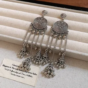Close-up of vintage silver circular bell tassel earrings with ethnic Bohemian style