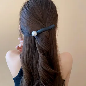 Elegant French style black hair clip with white pearl accent on long wavy brown hair