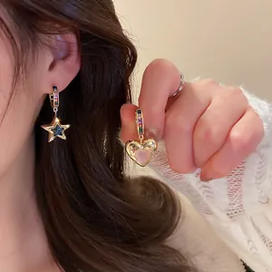 Détail de boucles d'oreilles asymétriques cœur et étoile avec pierres colorées