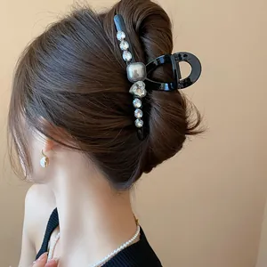 Back view of elegant black hair claw clip with faux pearls and sparkling rhinestones