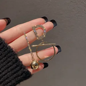 Vue rapprochée de boucles d'oreilles dorées asymétriques avec lettre D et formes géo