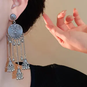Close-up of vintage silver tassel earrings with delicate bell charms and ethnic filigree.