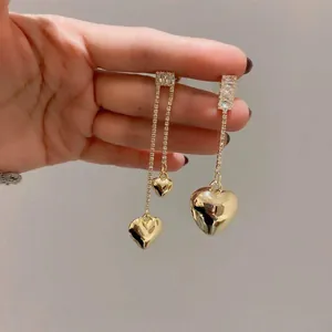 Gros plan détaillé de boucles d'oreilles cœur dorées avec des pierres de zircone.