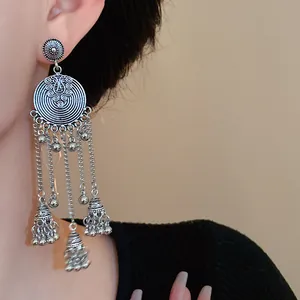 Close-up of vintage Bohemian silver bell tassel earrings worn by a model