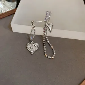 Gros plan sur d'élégantes boucles d'oreilles cœur argentées avec de brillants pompons en cristal.