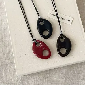 Detail of three resin hollow oval pendants in black, red, and tortoiseshell colors