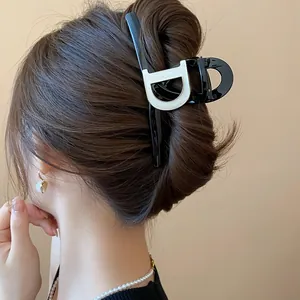 Close-up detail of a French style black hair claw clip with white D-logo design