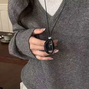 Close-up of a minimalist black resin hollow oval pendant necklace on a grey sweater.