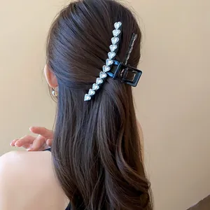 Close-up of elegant black hair claw clip with clear heart rhinestones on long hair.
