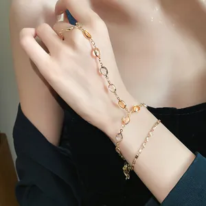 Detailed view of an elegant gold-toned hand chain featuring oval resin stones on a model
