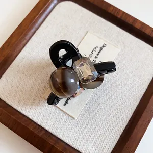 Macro view of French style black hair claw clip with brown agate-like bead and crystal