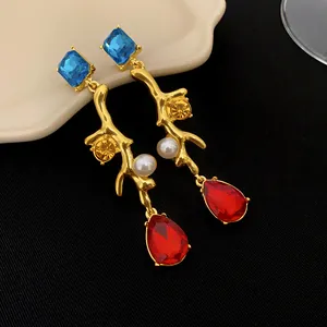Gros plan de boucles d'oreilles vintage dorées avec perles et pierres précieuses colorées.