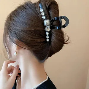 Close-up of elegant black hair claw clip with rhinestones worn in a bun hairstyle.