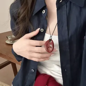 Close-up of a dark red resin oval pendant with hollow design on a model