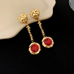 Gros plan de boucles d'oreilles vintage dorées avec cœur et pierre rouge