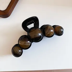 Close-up detail of a French style black hair claw clip decorated with amber beads.