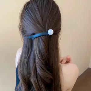 Detail of elegant French style black hair clip with white pearl on brown wavy hair