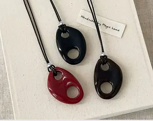 Macro detail of three colorful resin hollow oval pendant necklaces on textured background
